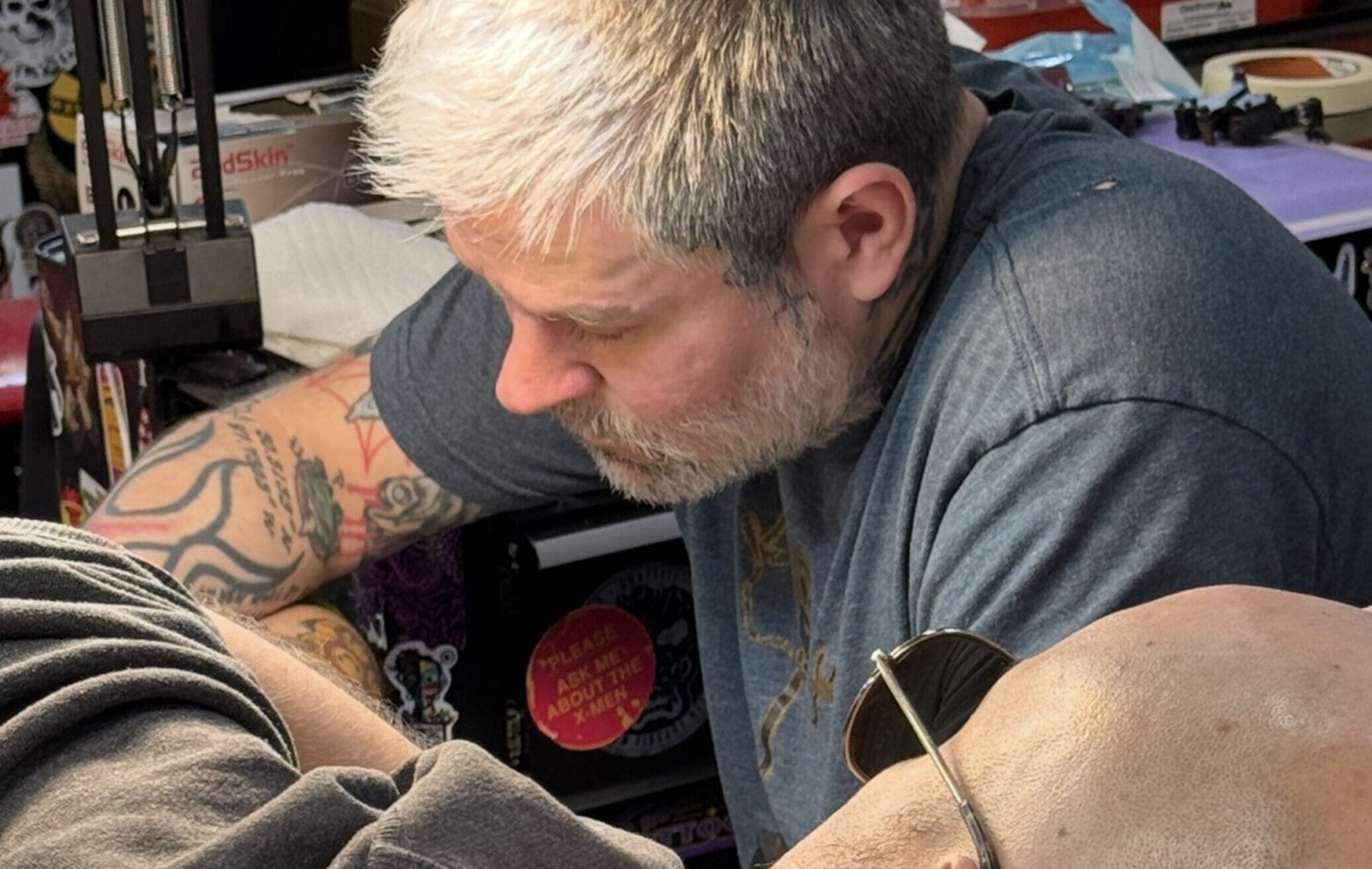 Custom color tattoo artist Shannon Ritchie tattooing a client's leg tattoo, done in nyc.